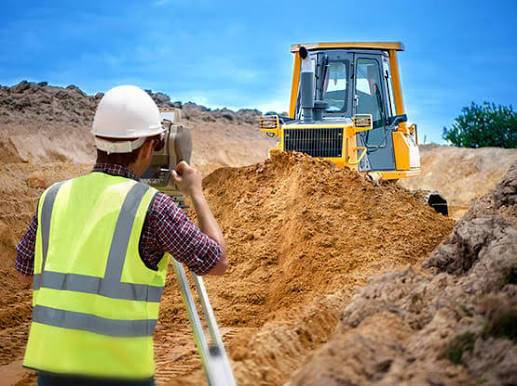 Surveyor coordinating grading work with construction equipment